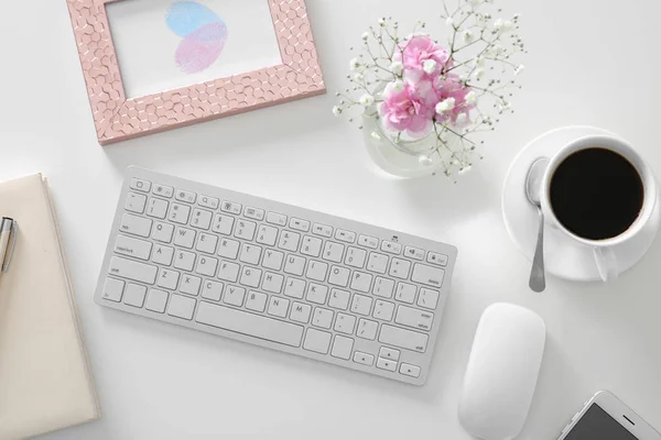 工作场所用电脑键盘和花束的美丽的粉红色的花朵在白色表上 顶部视图 — 图库照片