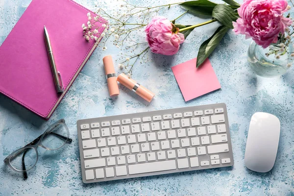 Workplace with computer keyboard and beautiful flowers on color table