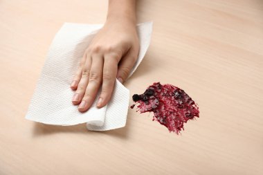 Kadın kağıt havlu ile ahşap masa üzerinde reçel nokta silme