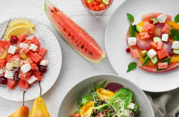 Plates with delicious watermelon salads on white table