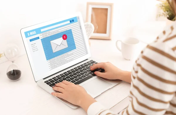 Young woman with laptop checking an email at home