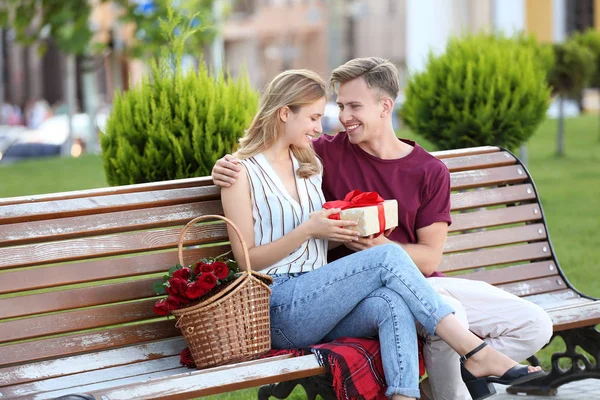 Young woman receiving gift from her boyfriend on romantic date outdoors