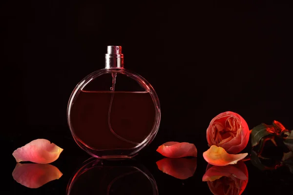 暗い背景に美しい花と香水のボトル — ストック写真