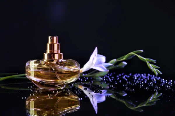 瓶香水与水滴和美丽的花朵在黑暗的背景下 — 图库照片