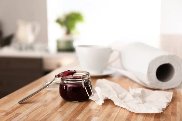 Roll of paper towels with jar of jam on kitchen table