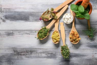 Farklı otlar ve ahşap masa haplarla kaşıklarla