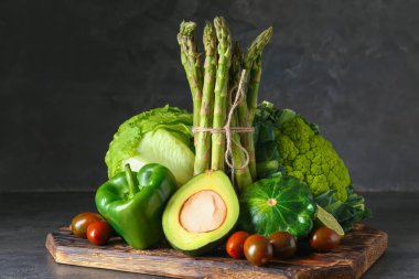 Gri tablosundaki çeşitli taze sebze ile ahşap tahta