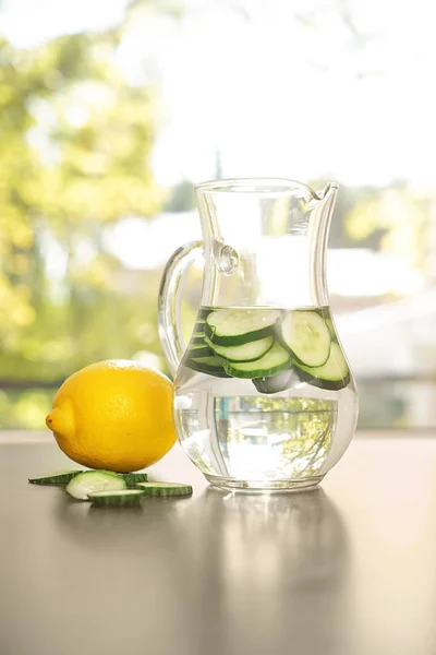 Jug of fresh cucumber water on grey table