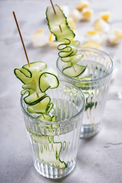 Glasses of fresh cucumber water on grey table