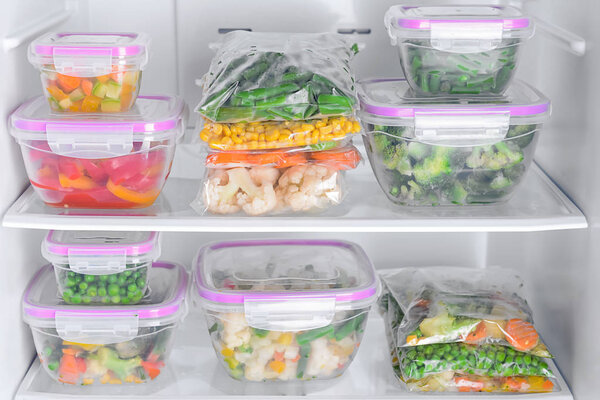 Контейнеры и пластиковые пакеты с замороженными овощами в холодильнике
