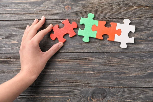 Main Féminine Avec Des Pièces Puzzle Sur Fond Bois — Photo