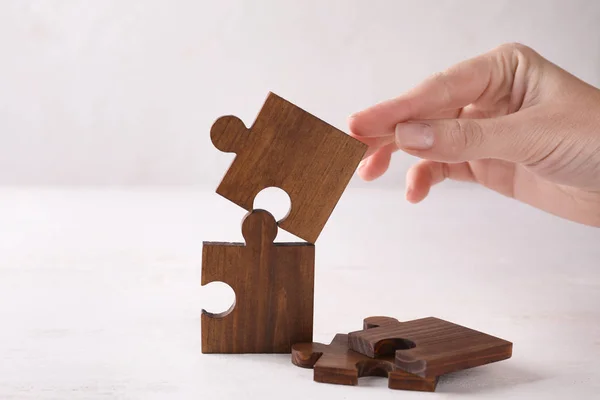 Vrouwelijke Hand Met Stukjes Van Houten Puzzel Lichte Achtergrond — Stockfoto