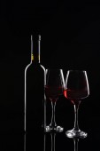 Láhve a sklenice červeného vína na tmavém pozadí