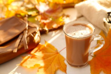 Işık masada cam fincan sıcak kahve ile sonbahar yaprakları