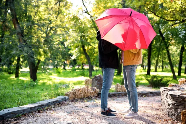 Happy gay couple with umbrella in park