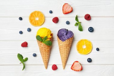 Gözleme koniler ile lezzetli renk dondurma, meyve ve çilek Beyaz ahşap zemin üzerinde