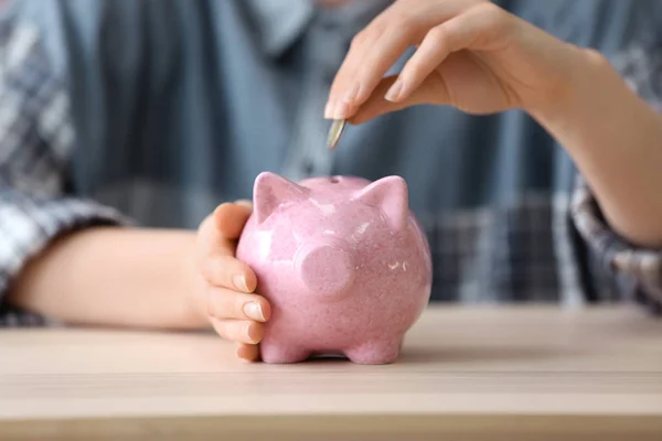 Woman Putting Coin Piggy Bank Wooden Table Closeup — Stock Photo, Image