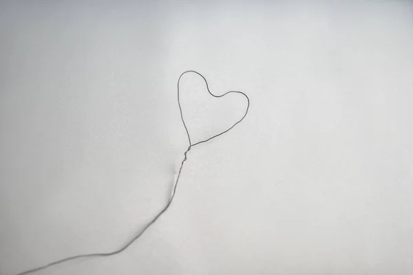 Heart made of wire on grey background