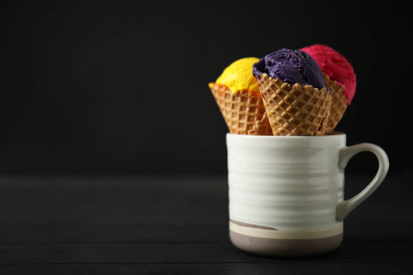 Waffle cones with delicious ice color cream in cup on wooden table