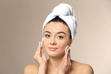 Güzel genç kadın ile ipeksi cilt renk arka plan üzerinde pamuk tamponlarla kullanarak