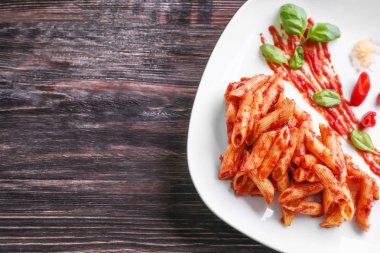 Plaka lezzetli penne makarna ve ahşap zemin üzerine sos ile