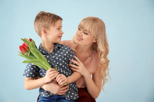 可爱的小男孩和他的母亲的肖像在灰色背景上的郁金香花束 — 图库照片