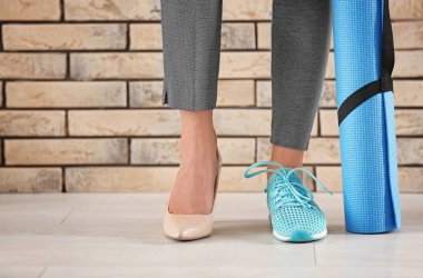 Yüksek topuklu ayakkabı ve tuğla duvar yakınındaki spor ayakkabı giyen genç kadın. Geri kalan çalışma arasındaki denge kavramı