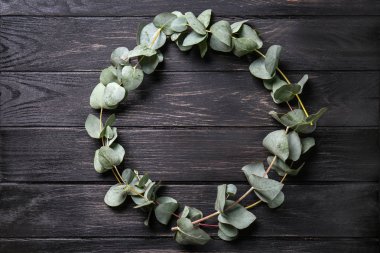 Koyu ahşap masa dallarda yeşil okaliptüs