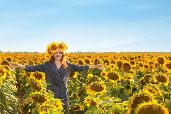 Beautiful redhead woman in sunflower field on sunny day