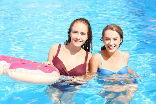 Beautiful young women with inflatable ring in swimming pool