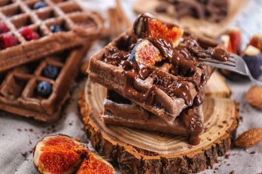 Lezzetli waffle incir dilimleri ve ahşap tahta üzerinde çikolata sosu ile