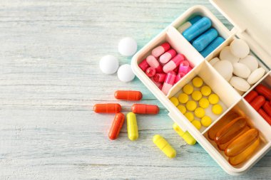 Ahşap arka plan üzerinde haplarla Plastik Konteyner