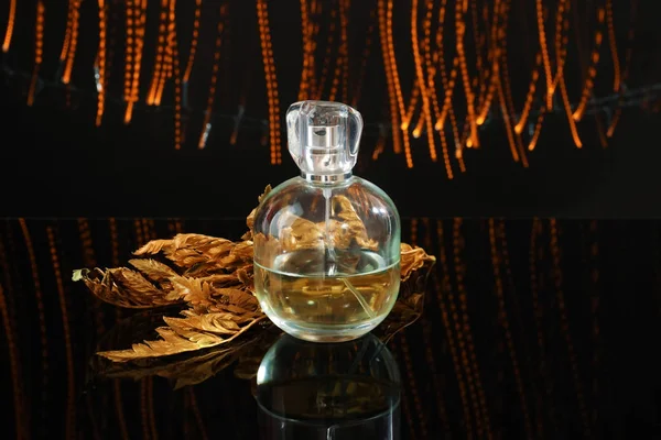 Altın Yaprağı Koyu Arka Plan Üzerinde Köpüklü Parfüm Şişe — Stok fotoğraf