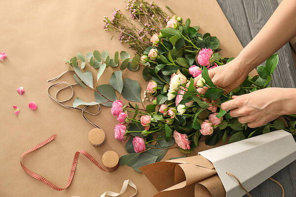 Female florist preparing bouquet of beautiful flowers on table