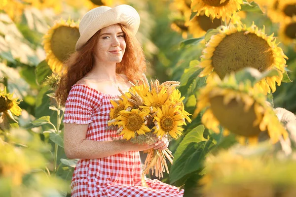 Beautiful redhead woman in sunflower field on sunny day