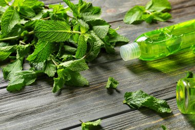 Ahşap masa üzerinde taze nane ile uçucu yağ şişe