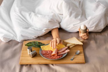 Uykulu kadın yatakta lezzetli breakfast battaniyeyle altında