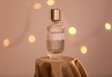 Bulanık ışıklar karşı parlak kumaş üzerine parfüm şişe