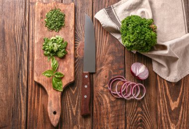 Soğan ve kesme tahtası ahşap arka plan üzerinde taze aromatik bitkiler