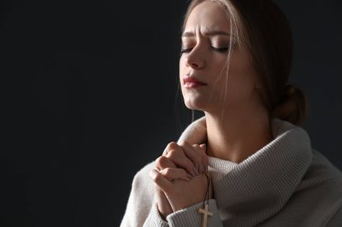 Güzel genç kadın koyu arka plan üzerinde dua