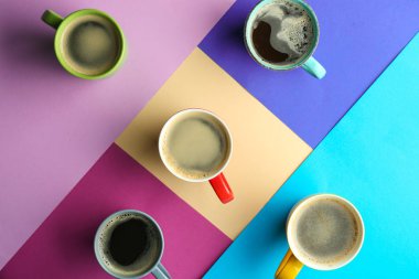 Düz renkli arka plan üzerinde lezzetli aromatik kahve ile fazla bardak yatıyordu