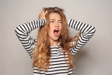 Işık arka plan üzerinde baş ağrısı muzdarip güzel genç kadın portresi