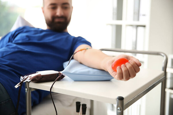 Man with grip ball donating blood in hospital