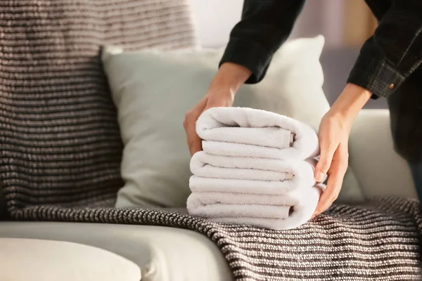 Beyaz temiz havlu yığını kanepenin üstüne koyarak kadın