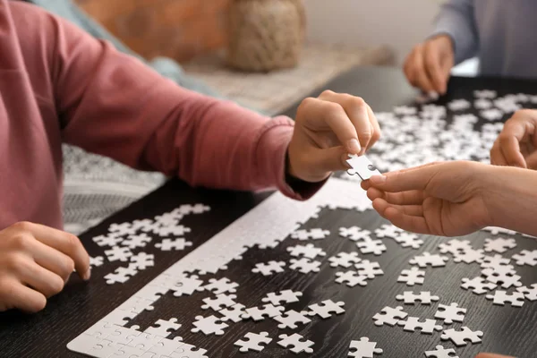暗いテーブルでパズルを組み立てる人のグループ — ストック写真