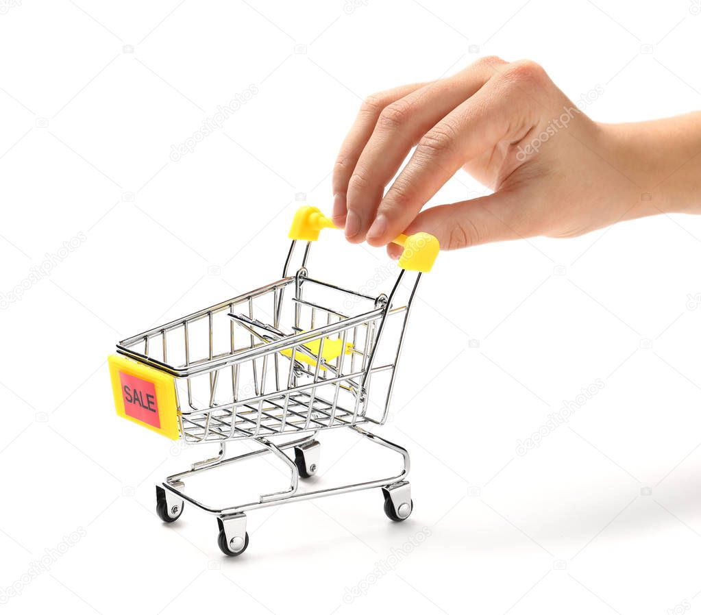 Female hand with small shopping cart on white background