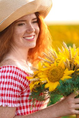 Ayçiçeği alan güneşli güzel kızıl saçlı kadın