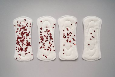 Gri arka plan üzerinde küçük kırmızı kalpler ile adet yastıkları