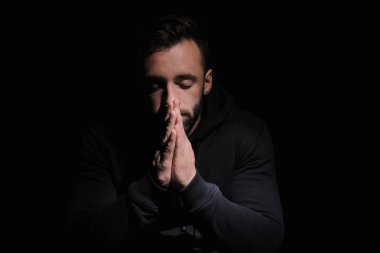 Siyah arka plan üzerine Tanrı'ya dua dini genç adam