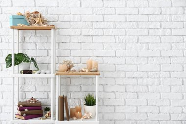 Kitaplarla, yanan mumlar, kabukları ve diğer süslemeleri yakınındaki beyaz tuğla duvar rafları
